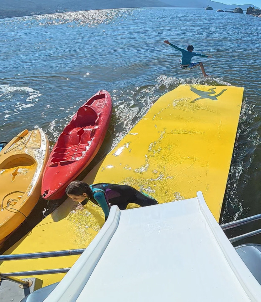 Turistas aproveitando o tapete mágico flutuante, caiaques e jet ski acoplados ao barco Borrachão em Florianópolis.