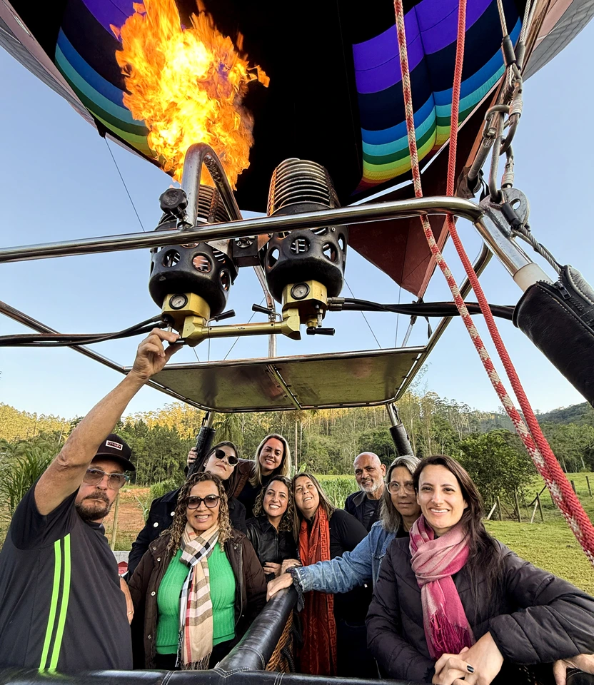 Grupo de passageiros no cesto de balão com chamas do queimador acesas antes da decolagem.
